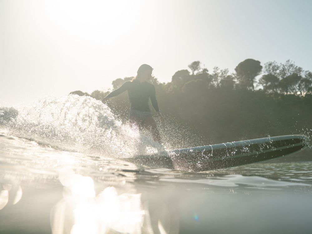 woman surfing a longboard  in morning light at point break Seal Rocks near Newcastle NSW