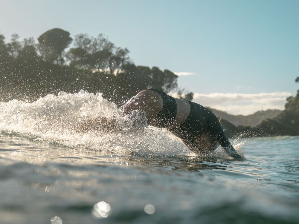 woman diving into the water from her surfboard at Seal Rocks near Newcastle NSW