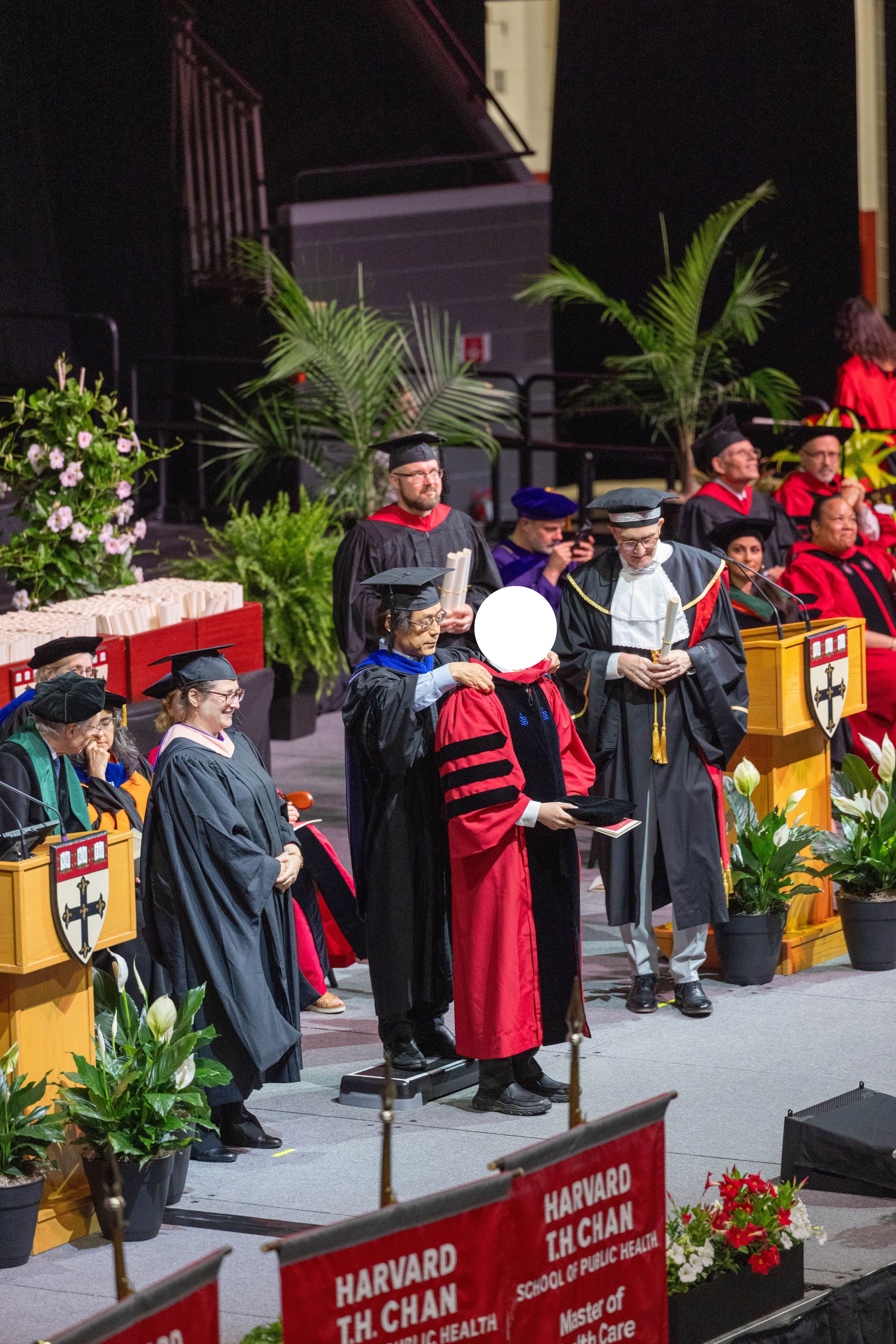 Harvard T.H. Chan School of Public Health graduation ceremony with faculty in academic regalia on stage.