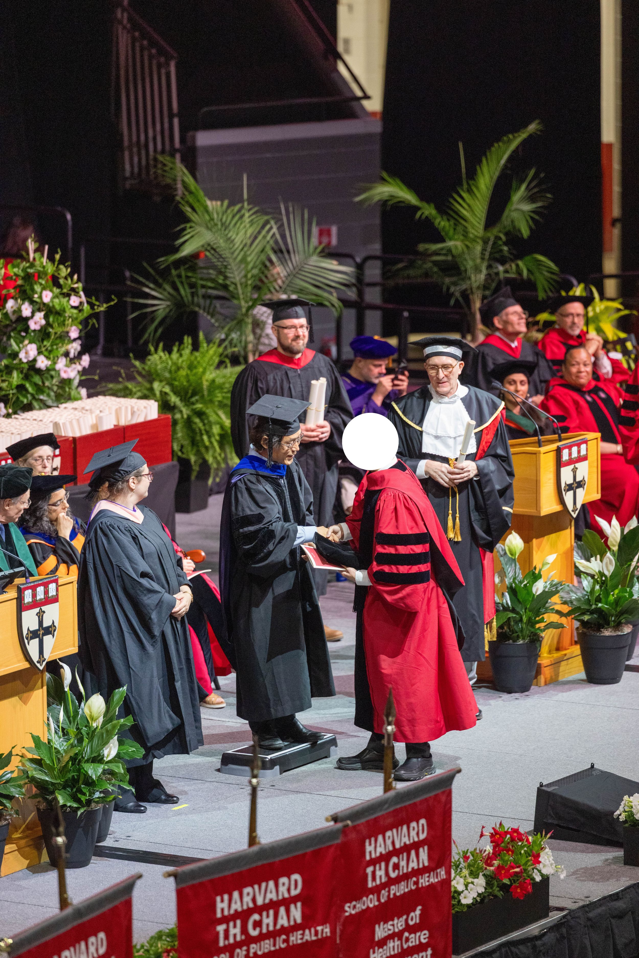 Graduate receives diploma on stage at Harvard T.H. Chan School of Public Health commencement ceremony.