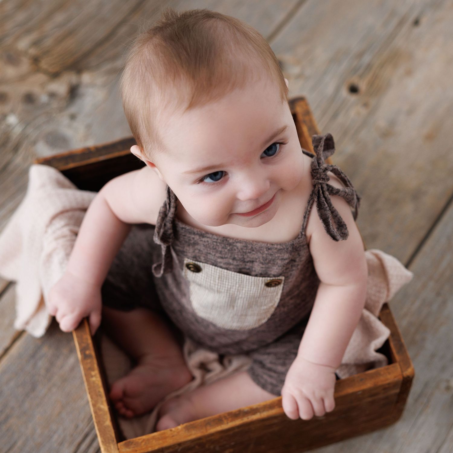 Baby girl with pink bow headband and pearl necklace touching her reflection in a white mirror outdoors.