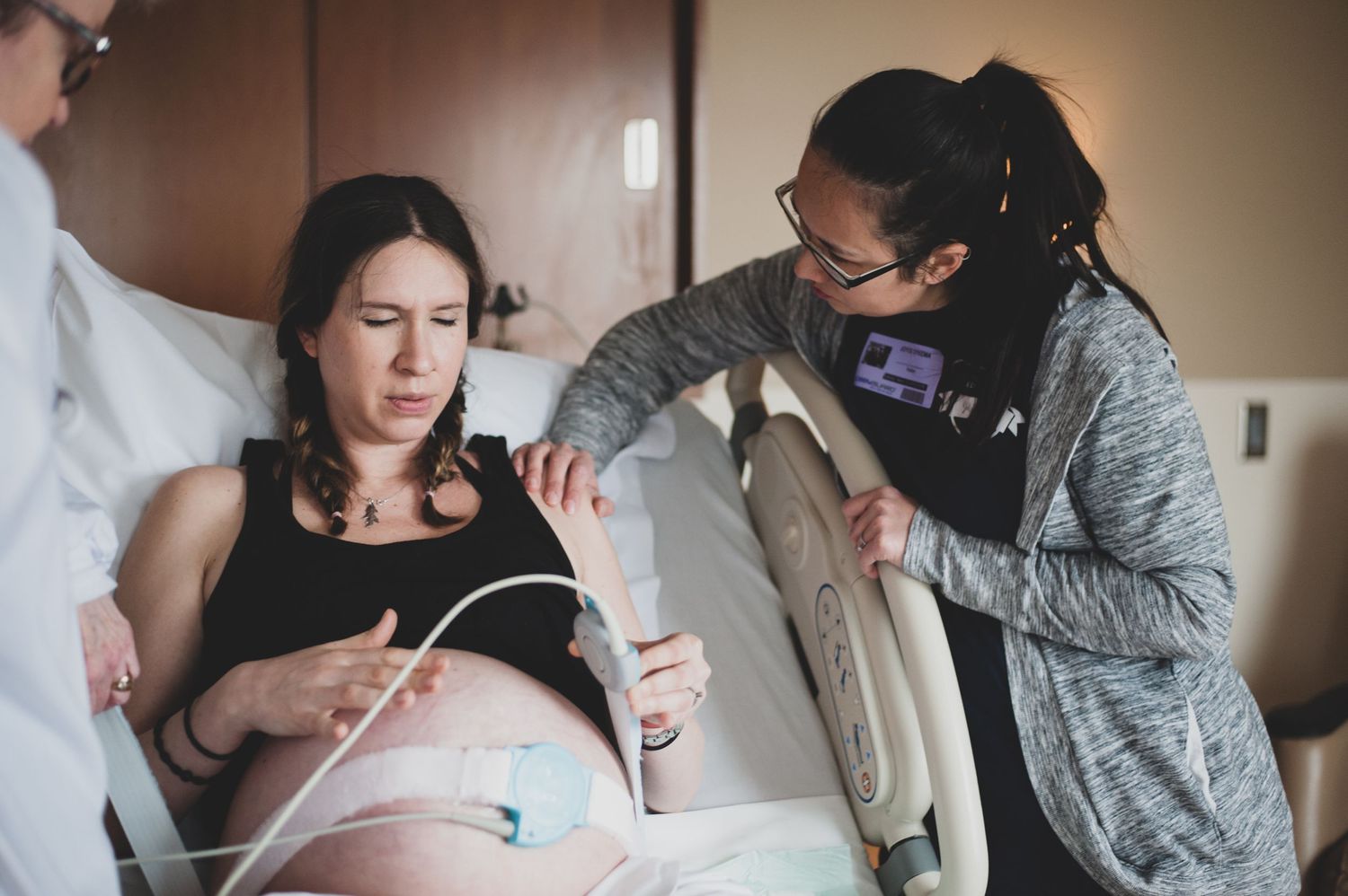 A tender moment during labor as a medical professional provides support in a hospital room.