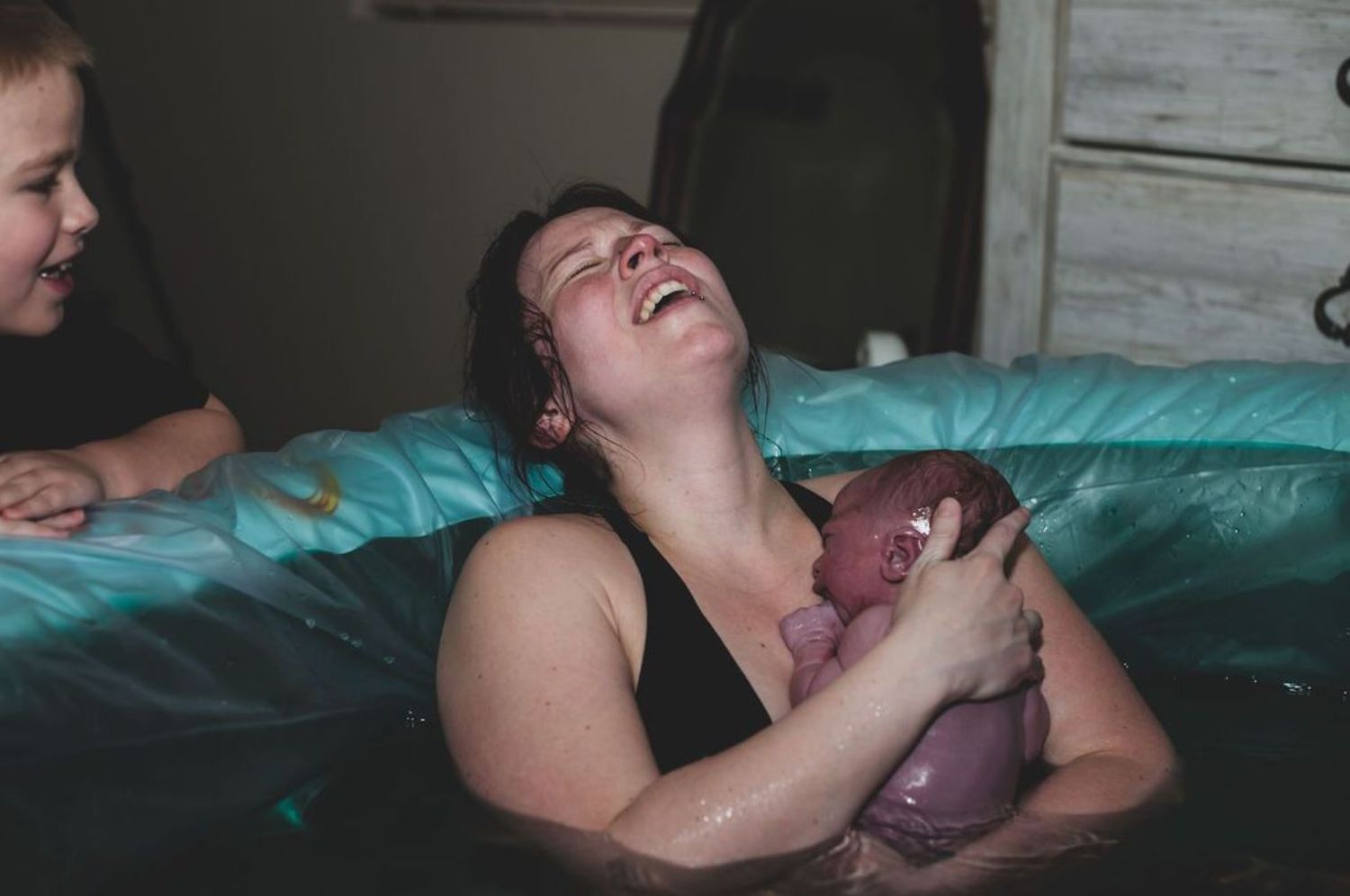 Emotional moment of joy as newborn baby is cradled after water birth.