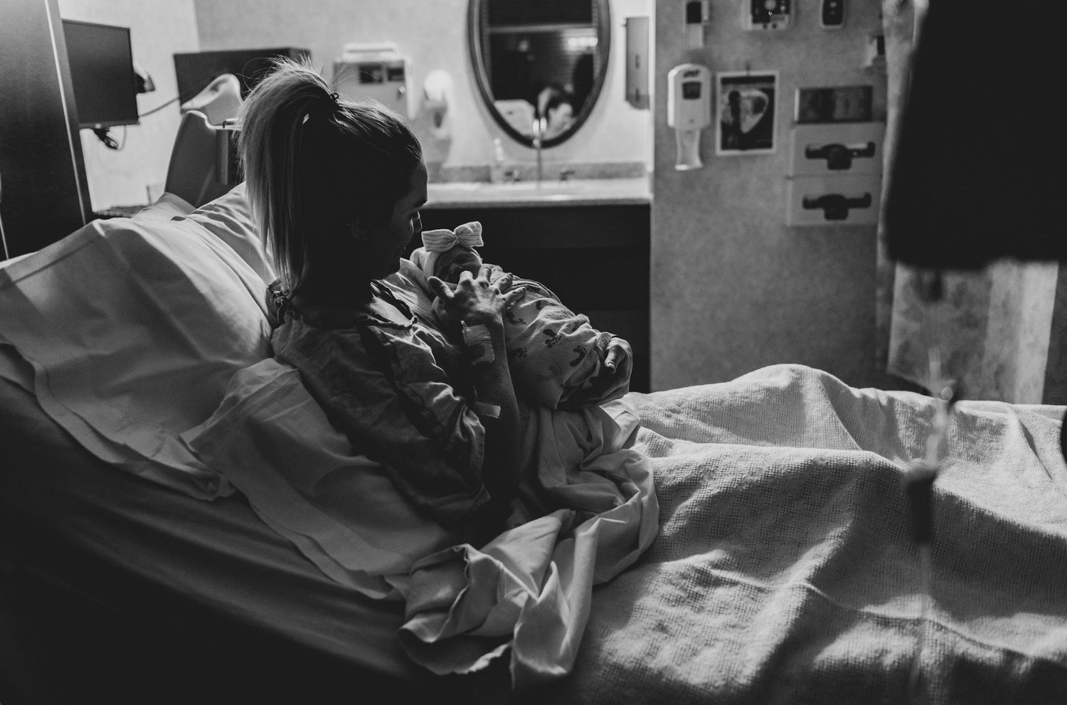 new mom cuddles her baby in the postpartum recovery room