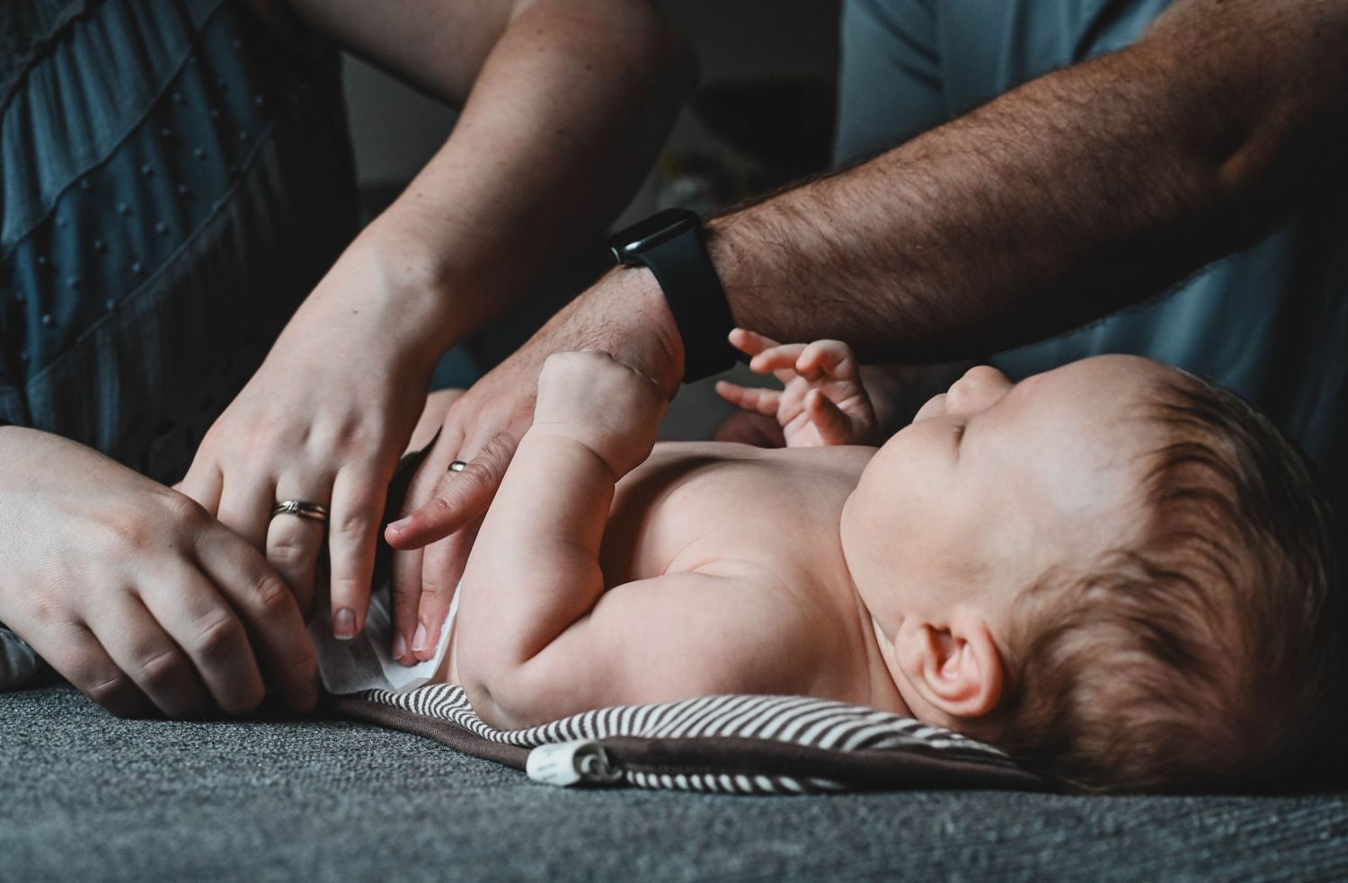 Mom changing newborn's diaper during in home newborn session in Hudson, NY