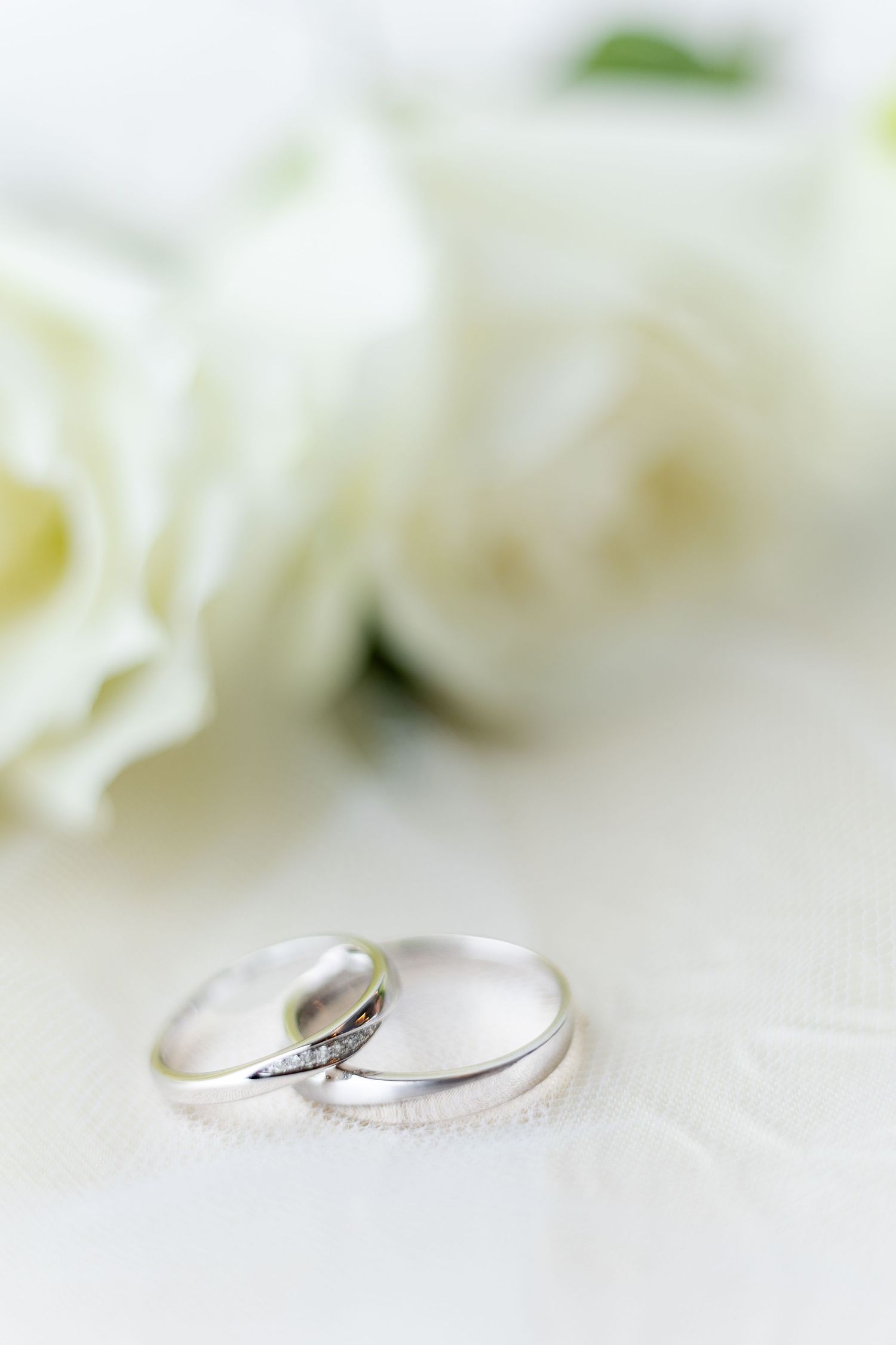 wedding photographer in singapore. bridal details, wedding ring in luxurious grey satin ring holder and white roses. bright airy photographs