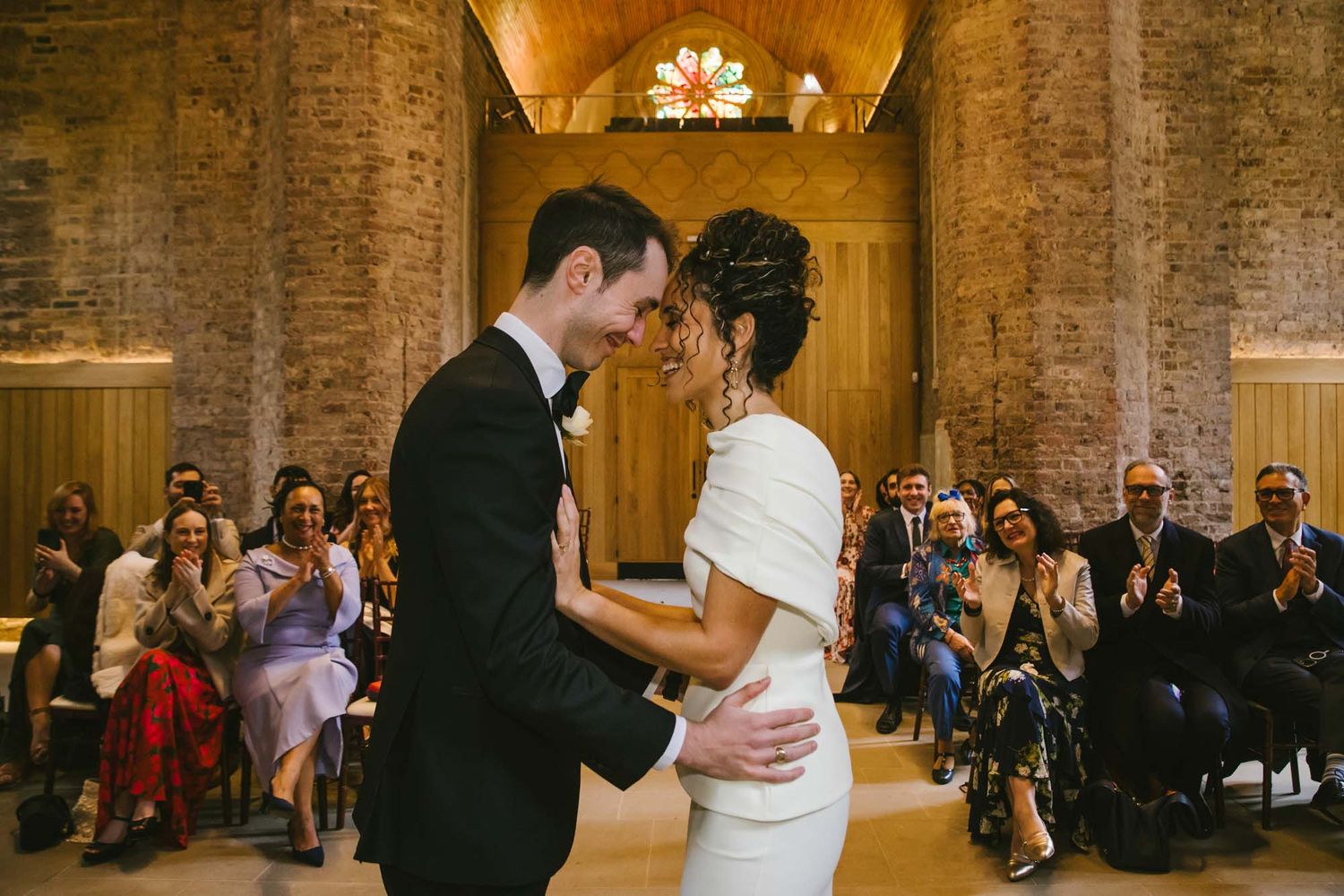 Couple exchanging vows at an elegant stone chapel wedding ceremony with candles and guests, at Abney park Chapel, Stoke Newington, Hackney