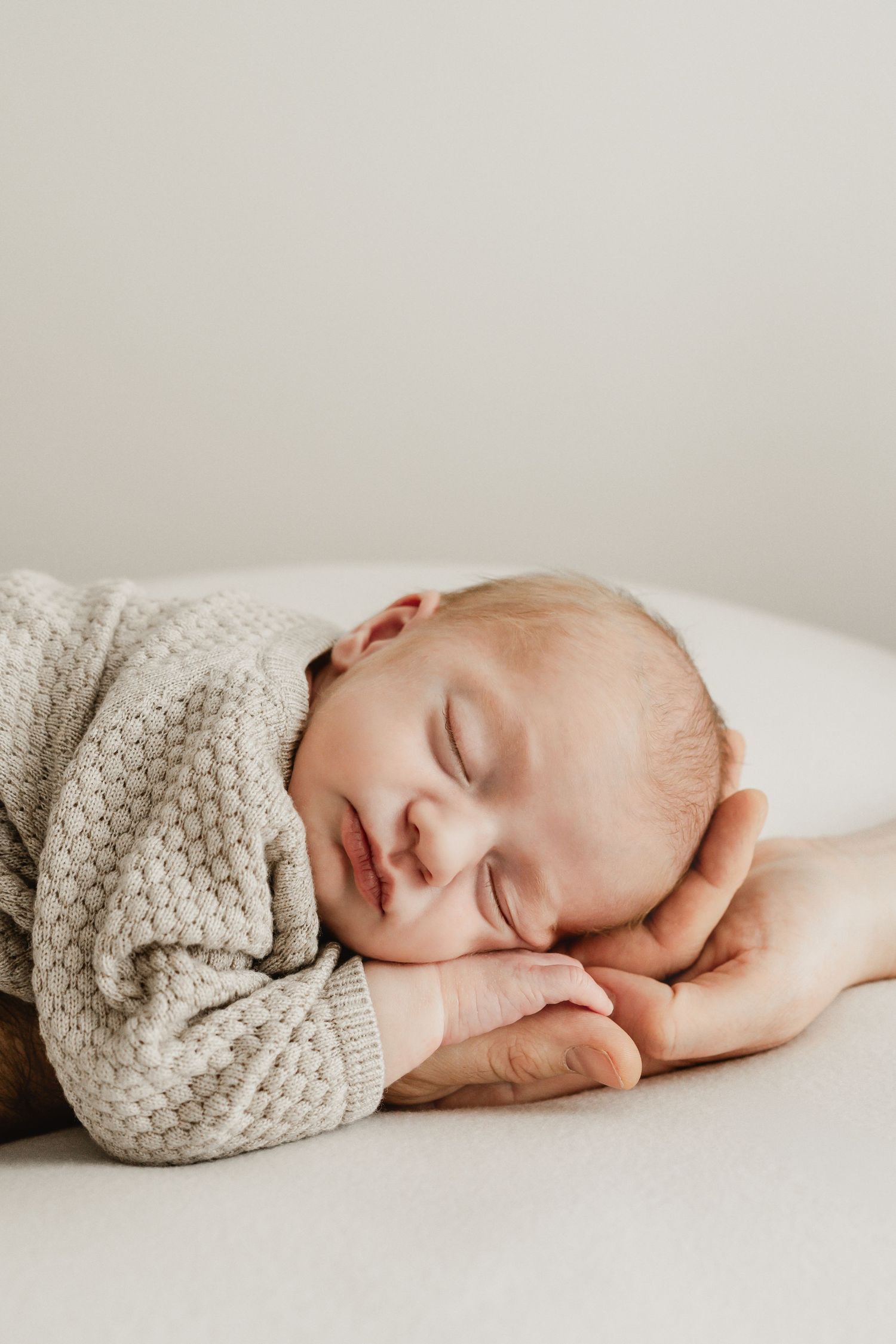 schlafendes Neugeborenes mit Köpfchen auf den Händen von Mama und Papa beim Neugeborenenfotograf Stockerau