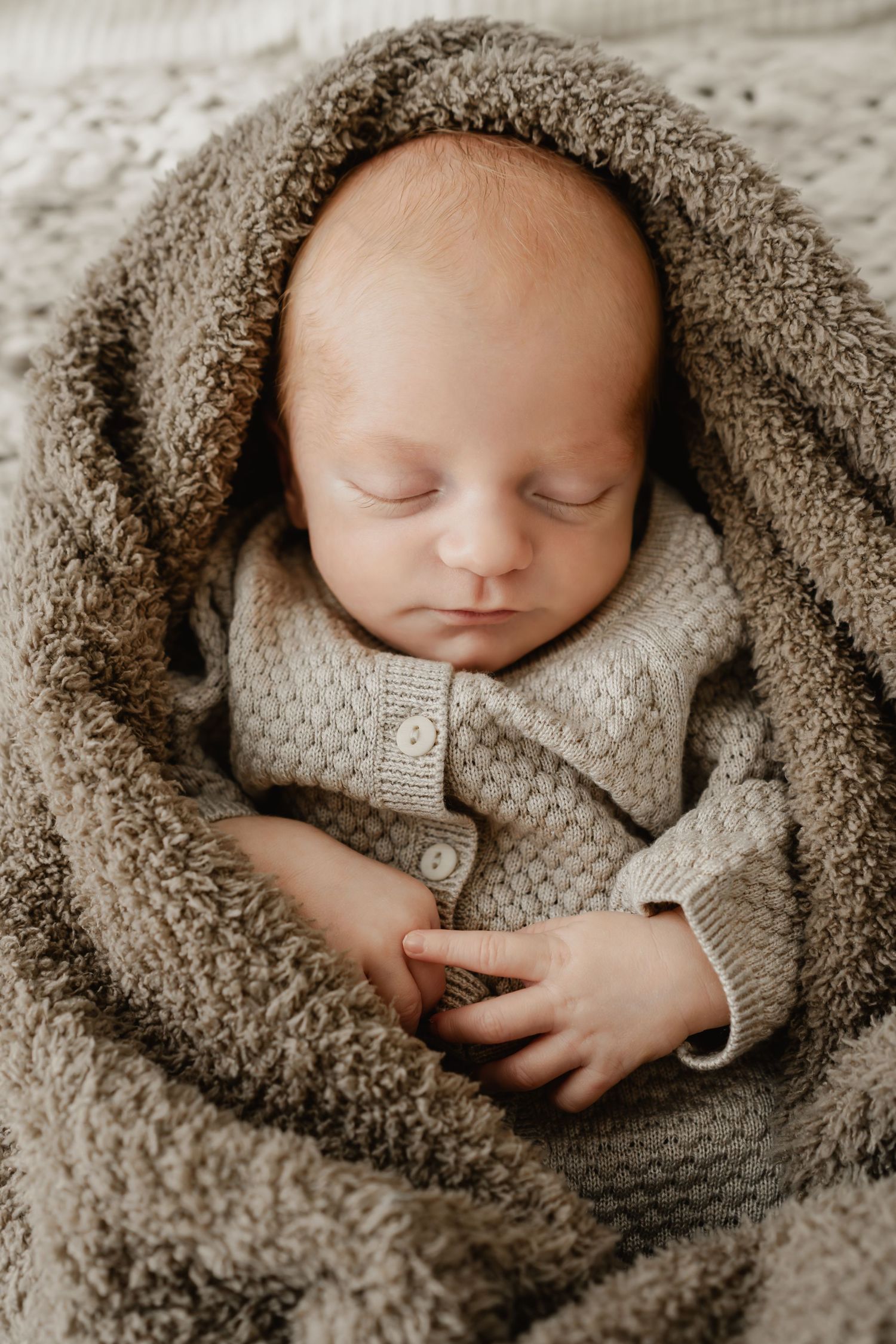 schlafendes Neugeborenes in kuschelige Decke gewickelt beim Babyfotoshooting Wien