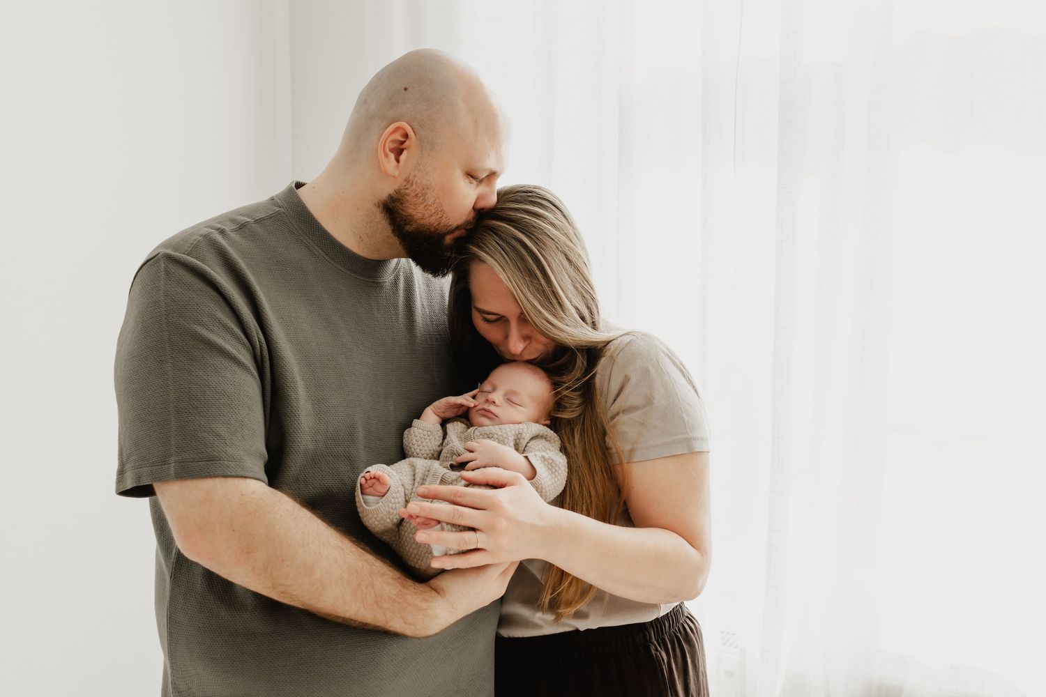 Familienfoto im Fotostudio Wien Eltern mit Baby im Arm und alle küssen sich gegenseitig