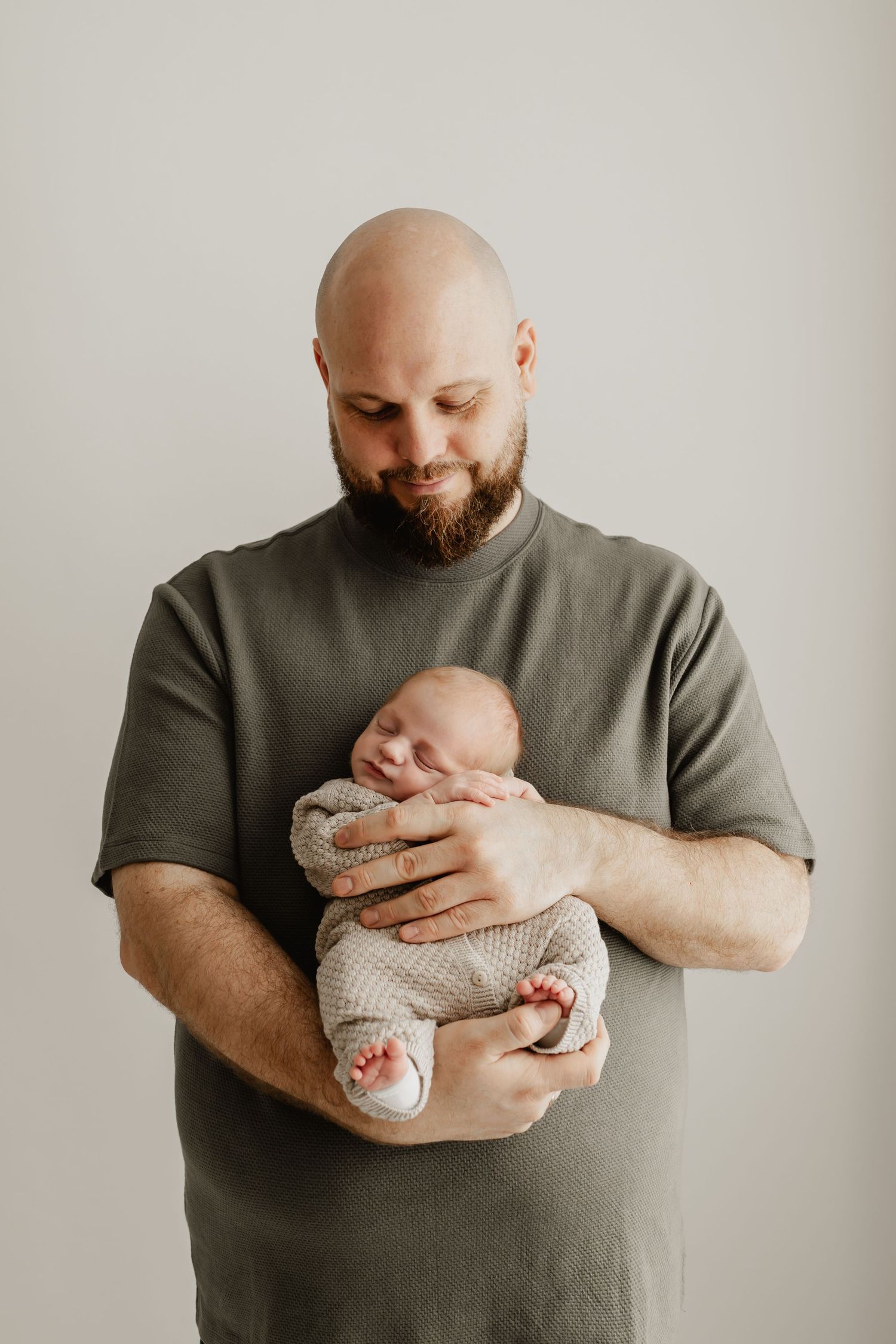 stolzer Papa mit Neugeborenem im Arm beim Babyfotoshooting in Stockerau mit Spreizhose
