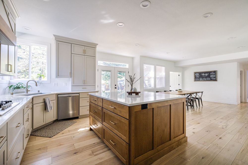 Spacious kitchen with gray shaker cabinets, warm wood island, white quartz countertops, and light hardwood floors.