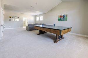 Spacious game room with ping pong table, pool table, vaulted ceilings, and neutral carpet flooring.
