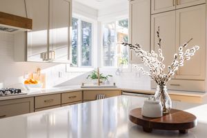 Modern kitchen with quartz countertops, beige cabinetry, white subway tile backsplash, and bay window.