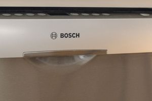 Close-up of Bosch appliance logo on stainless steel dishwasher door with handle detail.