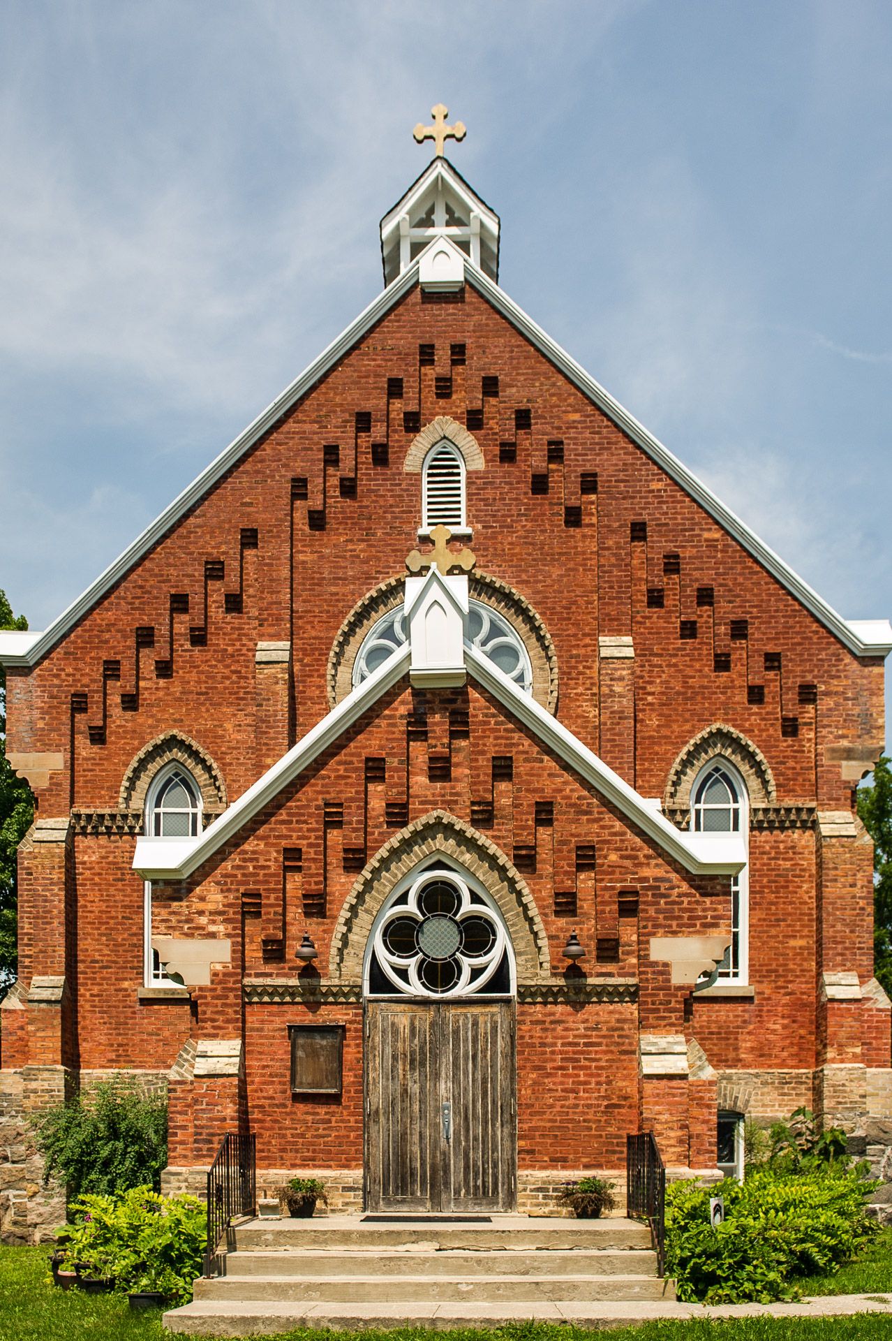 Historic red brick Orthodox church exterior with cross steeple.