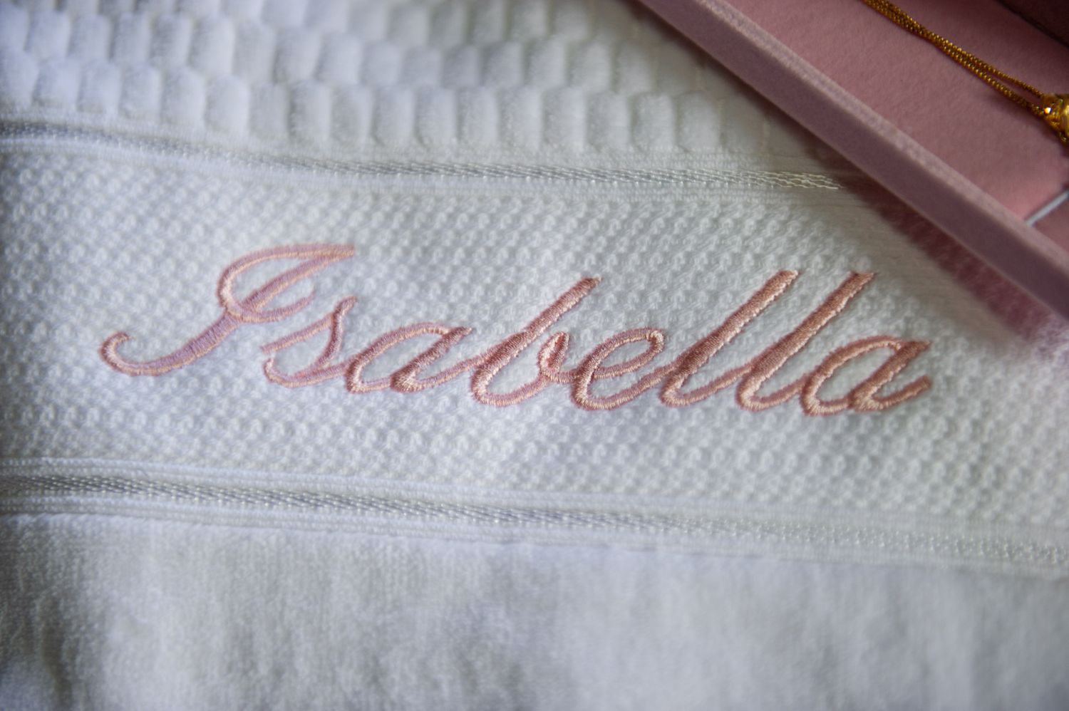 White baptism towel with Isabella embroidered in pink cursive script.