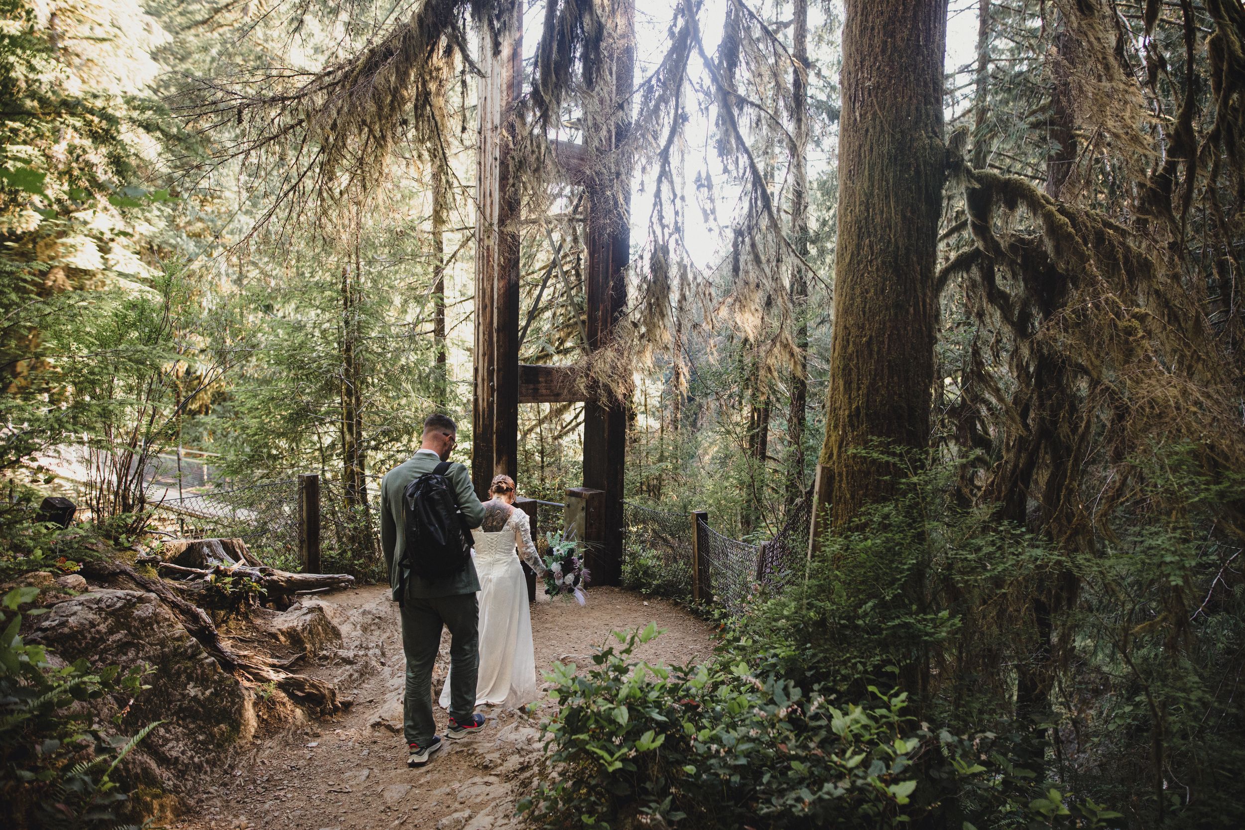 Bride and groom walk through towering redwood forest on their wedding day.