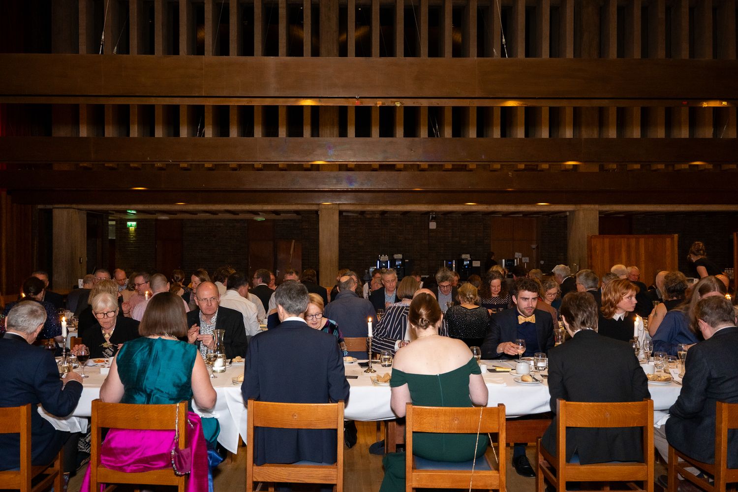 Elegant formal dinner event with guests seated at round tables in a warmly lit dining hall.