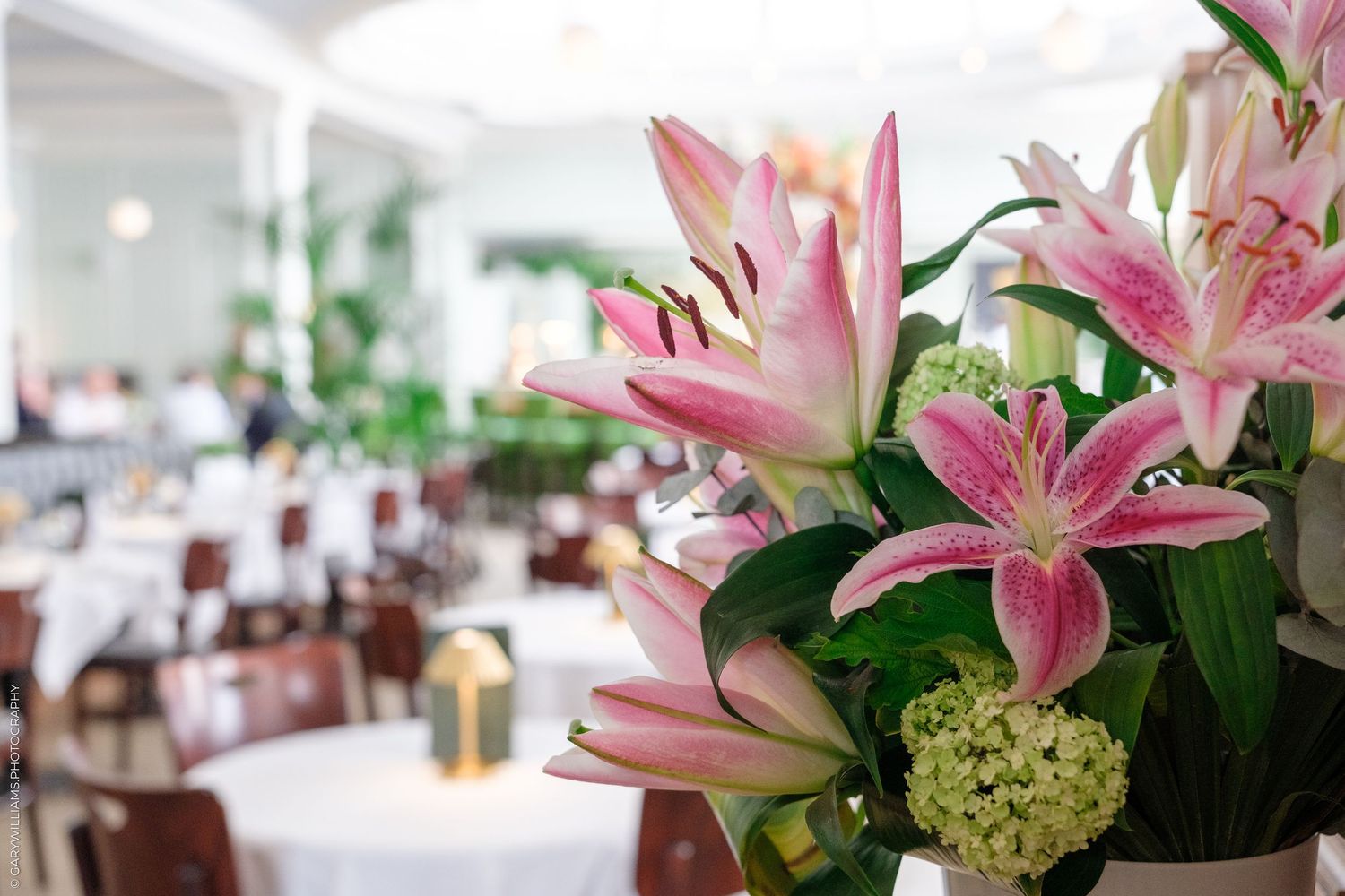 Pink stargazer lilies and white hydrangeas in a bouquet adorn 1 Lombard Street dining room with white tablecloths.