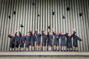 A group of young graduates in black robes toss their caps in the air during a joyful outdoor graduation ceremony.
一群身穿黑色畢業袍的年輕畢業生在戶外將畢業帽拋向空中