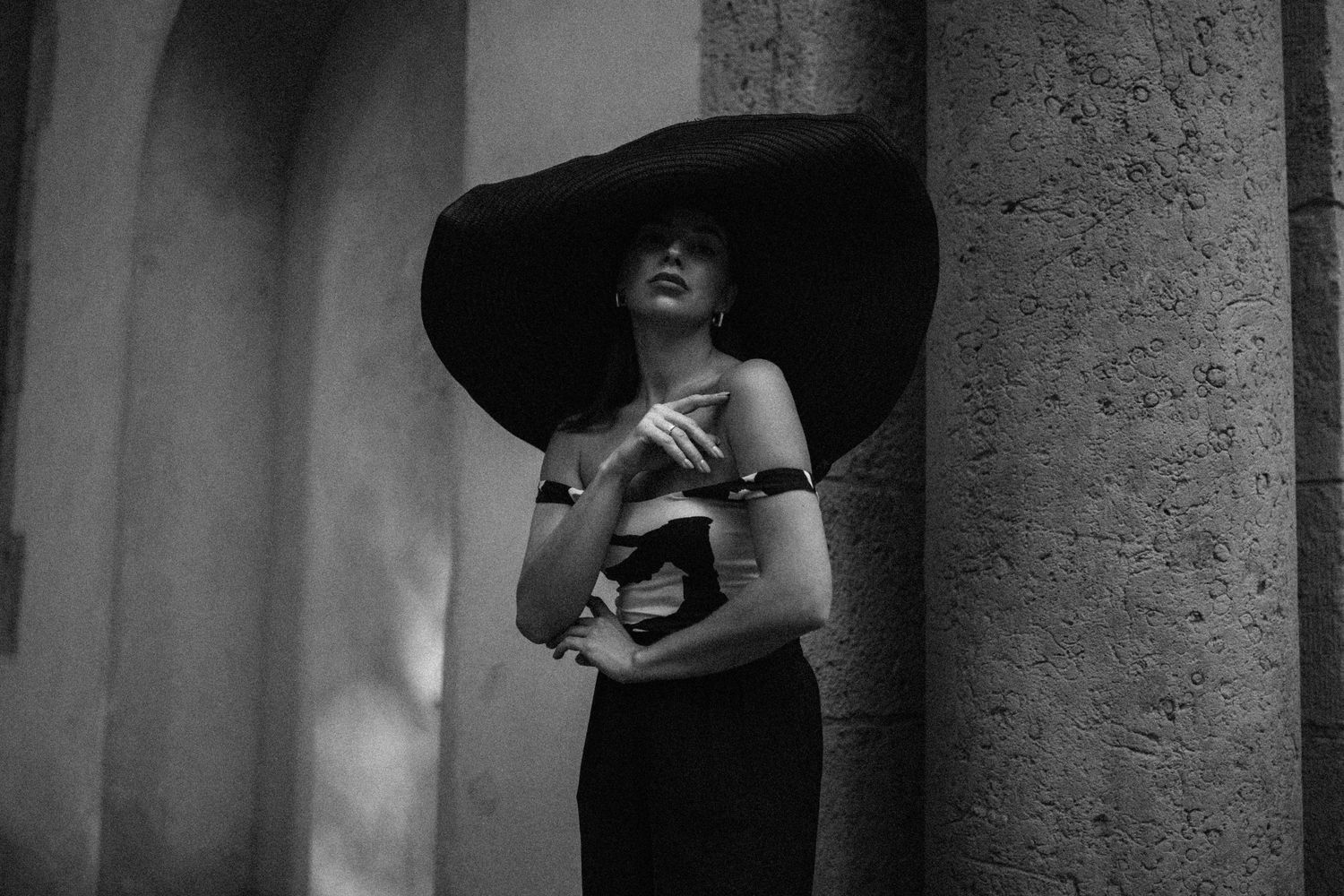 A dramatic black and white portrait featuring an oversized hat and elegant pose.