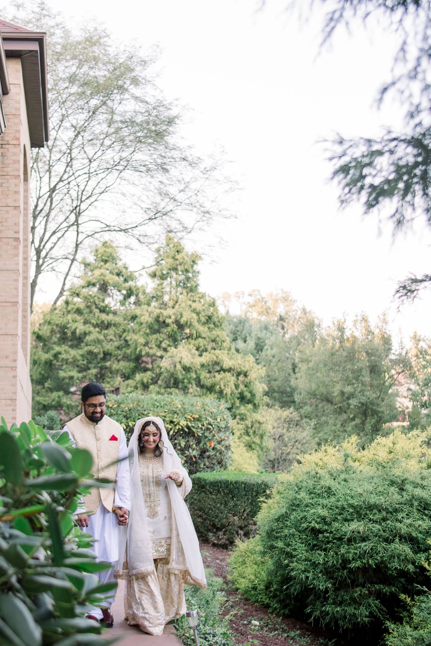Traditional South Asian wedding strolling along garden pathways surrounded by greenery. Pittsburgh Pa photographer nikah nikkah ceremony