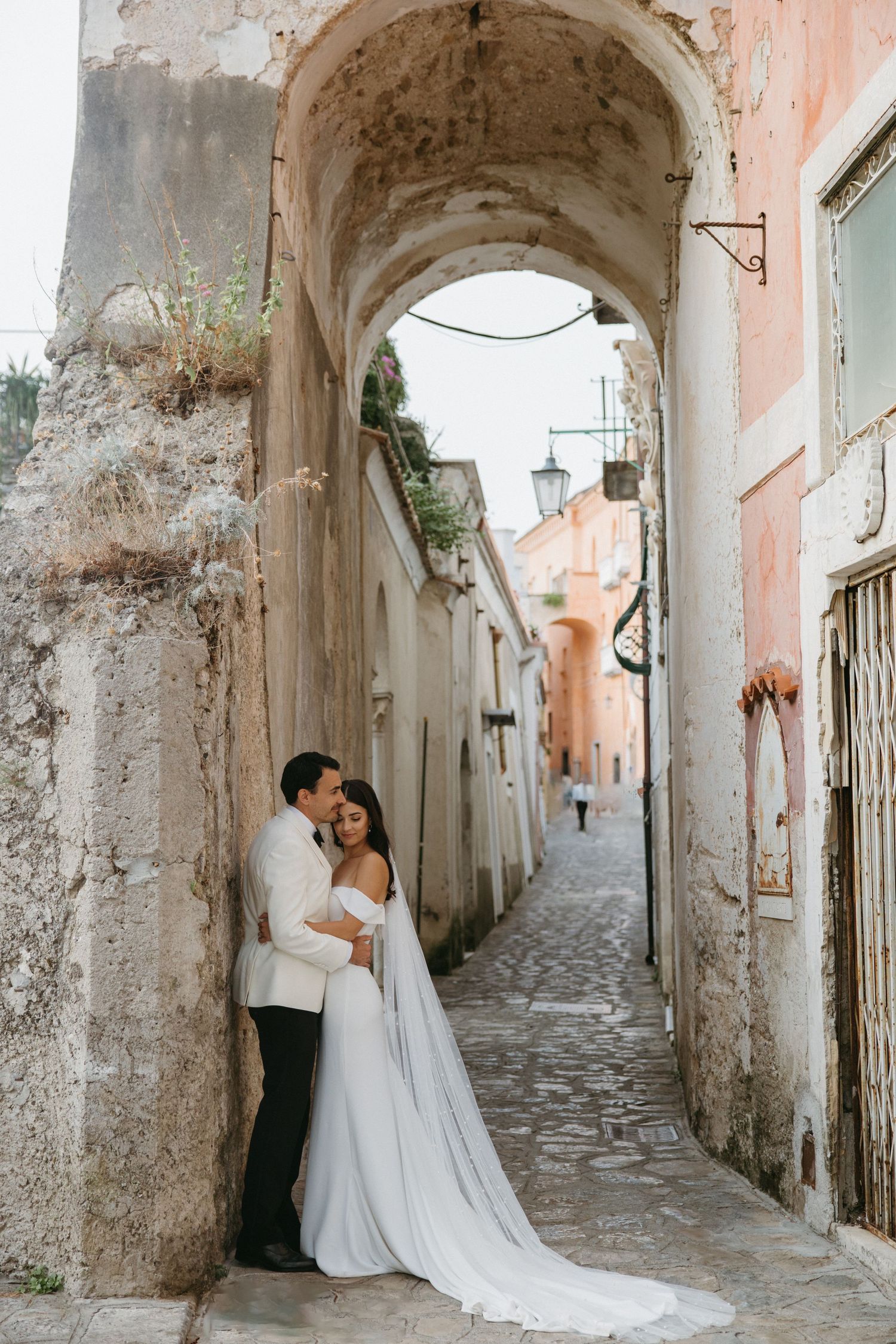 Romantic wedding photo captured in a narrow Italian alleyway with weathered stone walls.