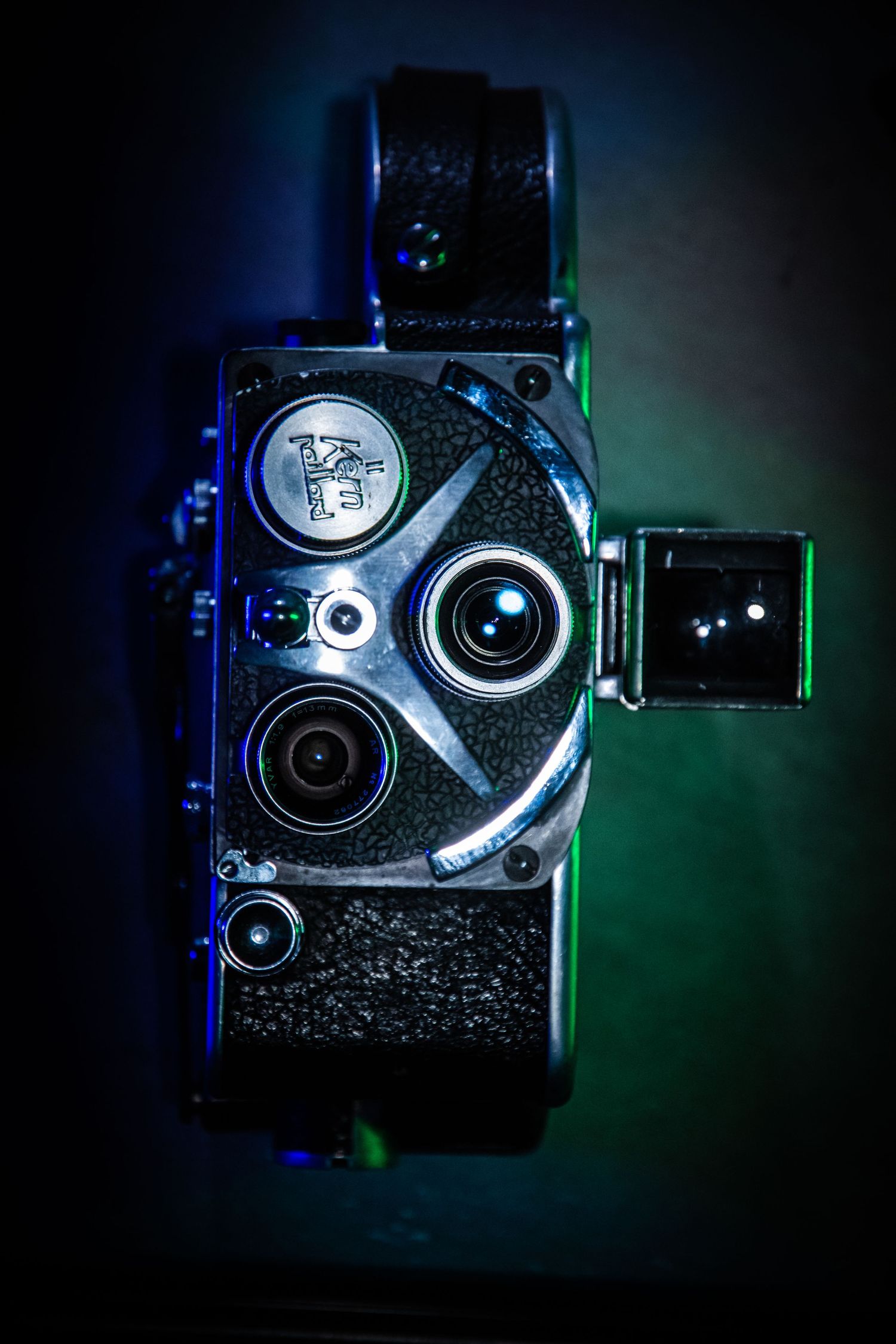 Vintage film camera with multiple lenses illuminated by dramatic colored lighting.