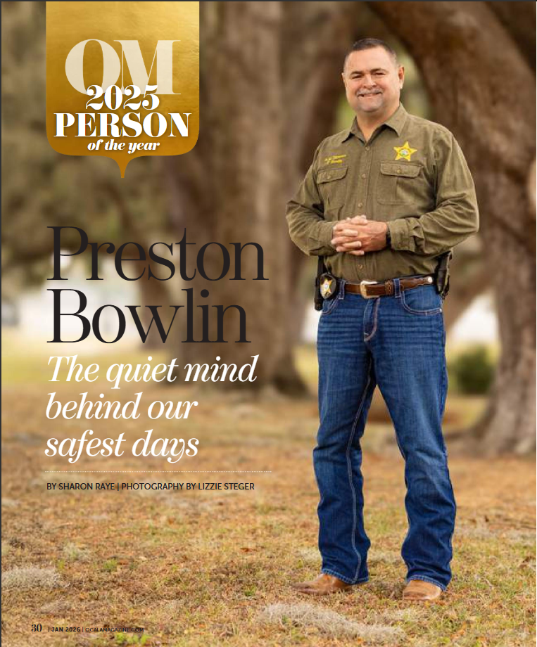 Preston Bowlin, QM 2025 Person of the Year, stands smiling in a sheriff uniform with jeans outdoors.