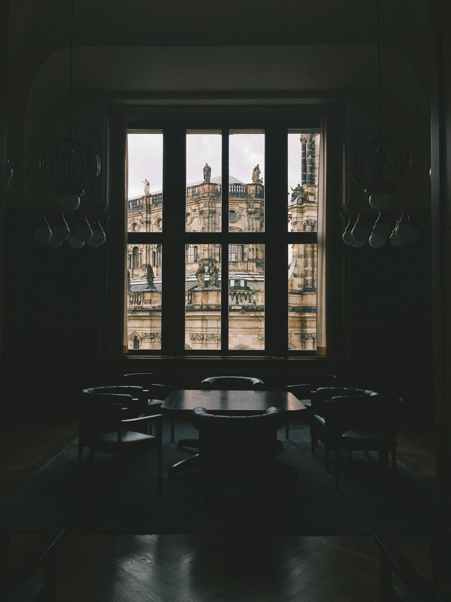 View through a dark window frame showing historic European architecture and buildings in daylight.