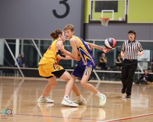 Players battle for ball possession during basketball game on indoor court.