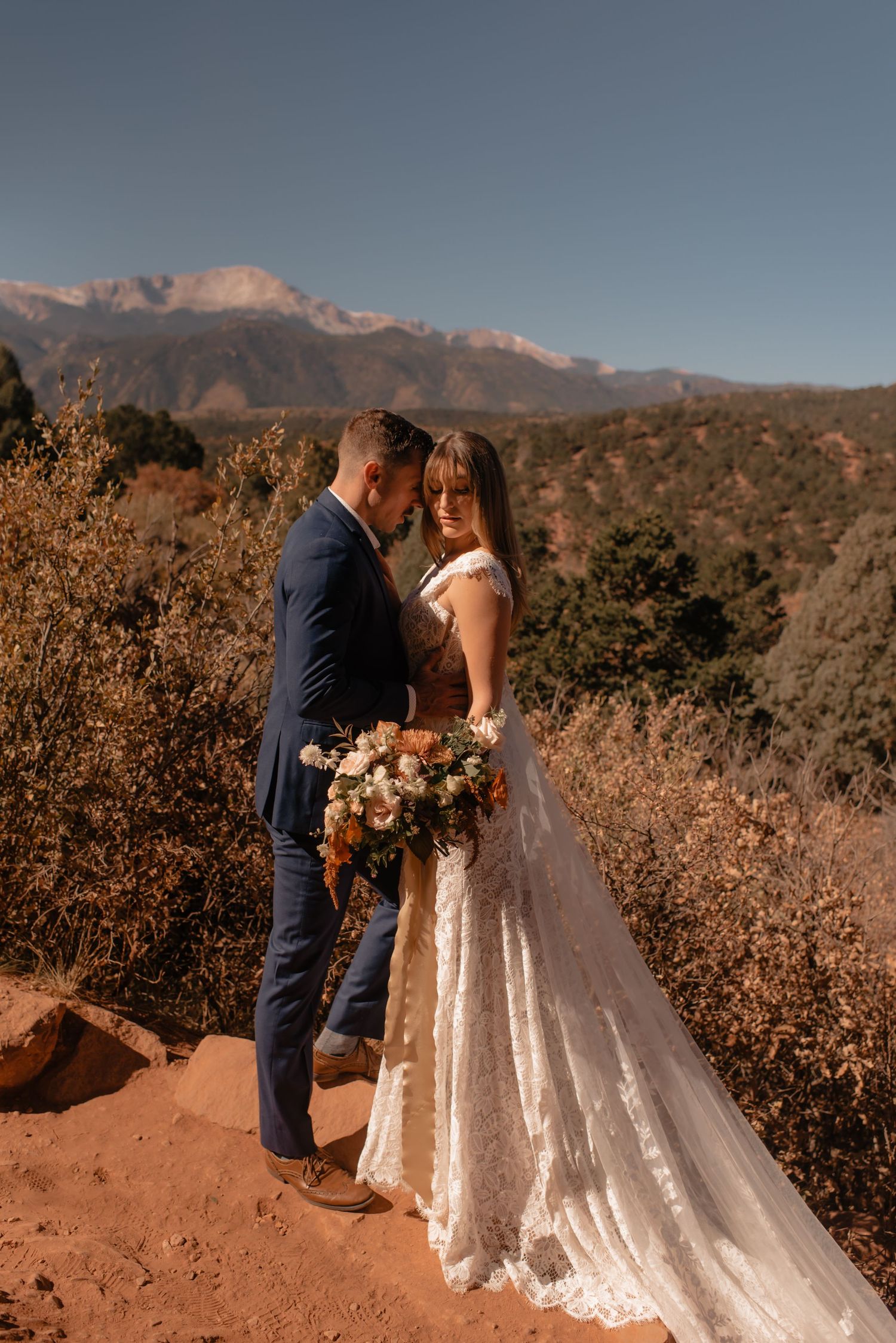 A bride and groom share an intimate moment against a mountainous backdrop during their Colorado sunset wedding.