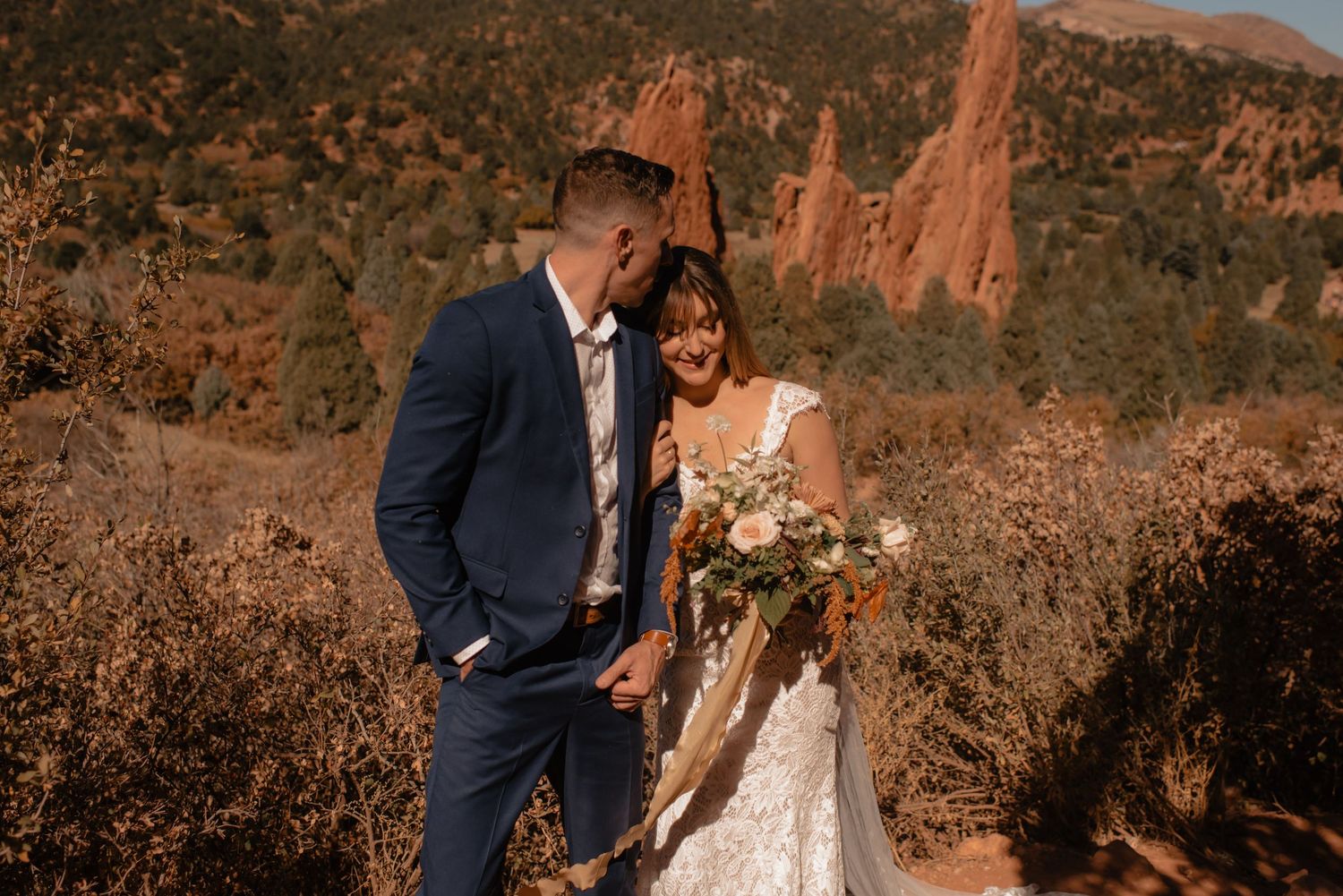 A romantic wedding couple poses in front of stunning red rock formations at sunset in Garden of the Gods.