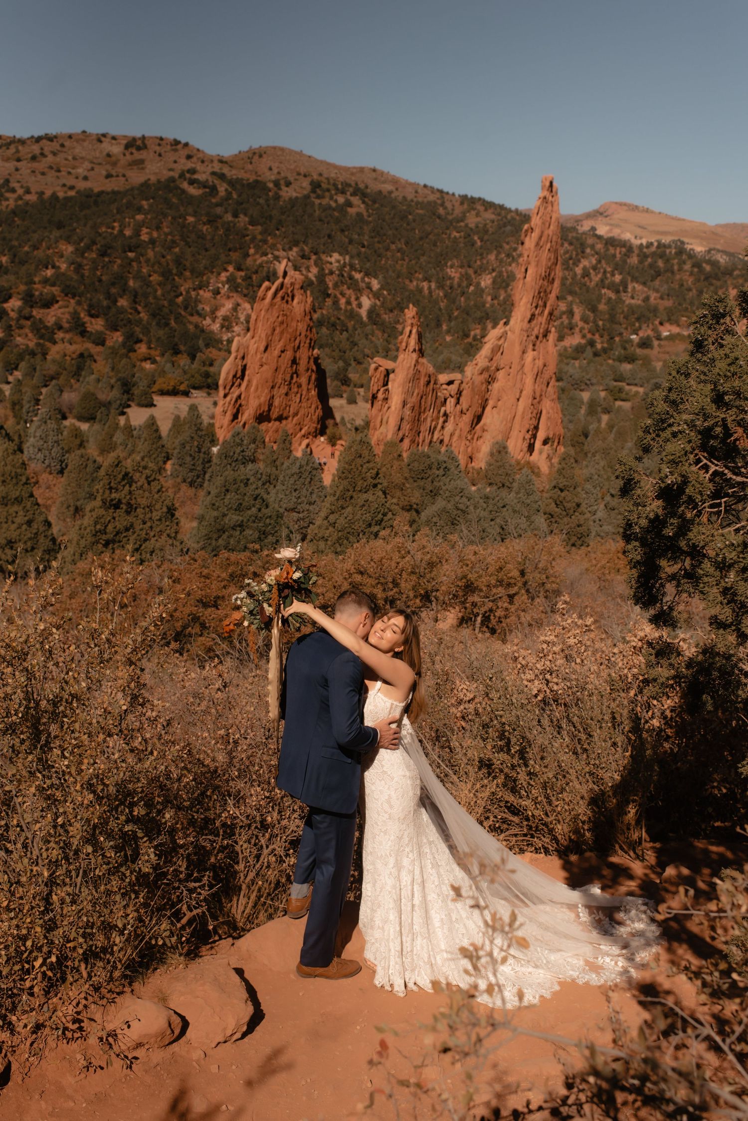 Newlyweds share intimate moment with dramatic red rock formations of Garden of the Gods behind them.