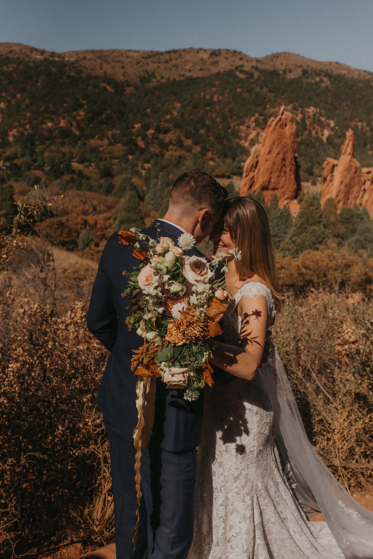 A couple shares a romantic moment at sunset in front of towering red rock formations at Garden of the Gods, Colorado.