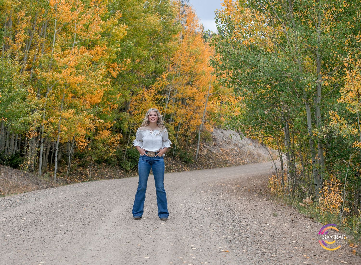 High School Senior posing on a curvy mountain road in the fall for her senior portrait session.