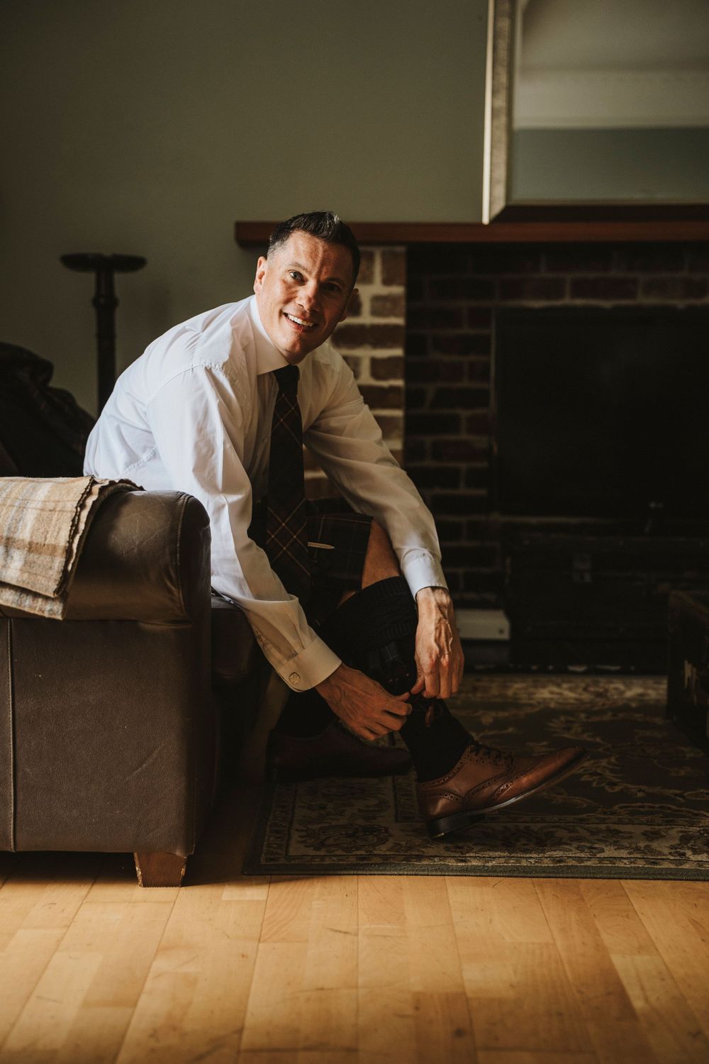 A series of moody portraits showing someone in formal attire reclining on a hardwood floor near a brick wall.