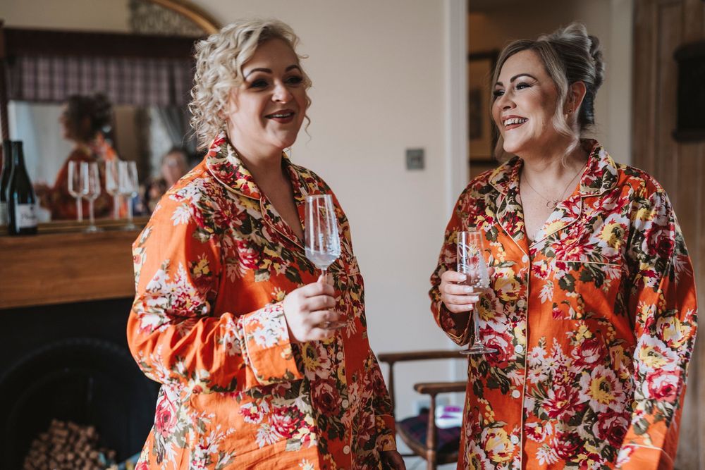 Two people laughing and enjoying a candid moment while wearing matching floral red and orange outfits.