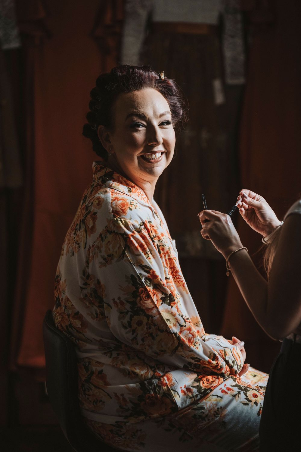 A candid moment during wedding preparations shows someone in a floral robe getting ready.
