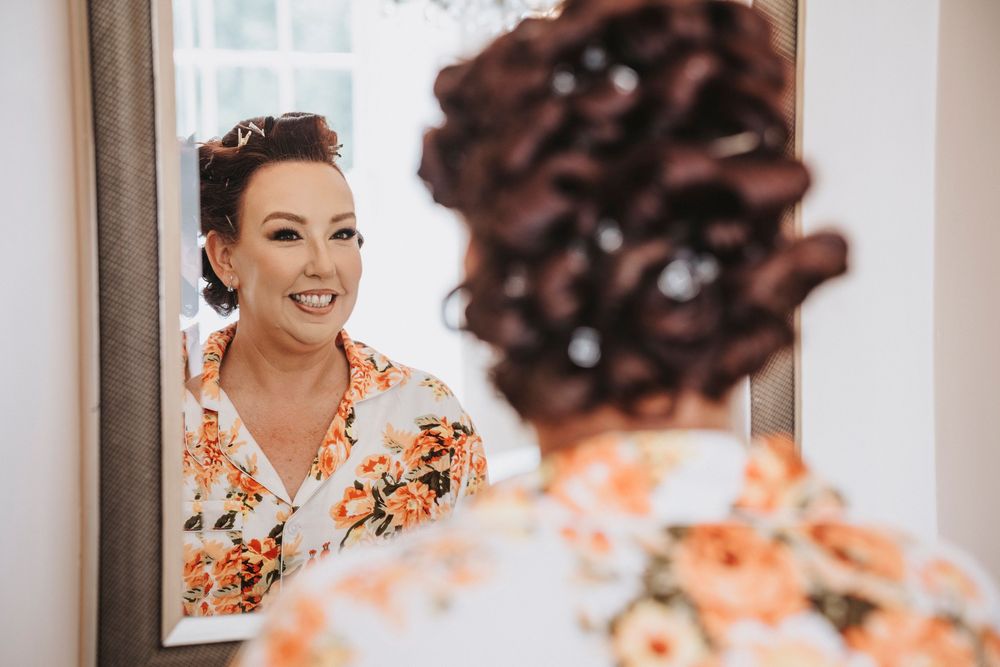 Bride gets her makeup professionally done while wearing a floral robe during wedding preparations.