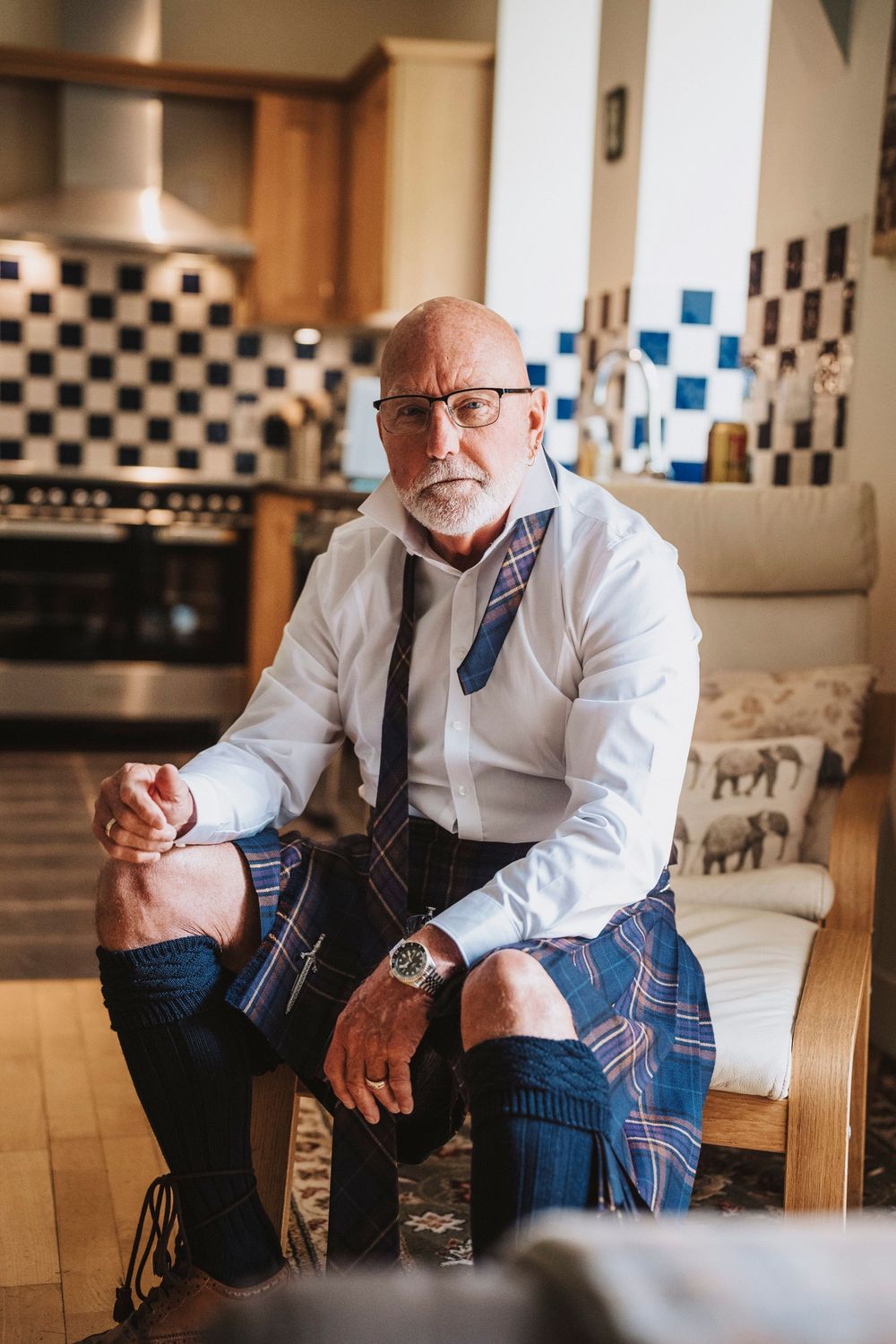 Candid sequence of a person in business attire and plaid pants sitting in a rustic kitchen with checkered walls.