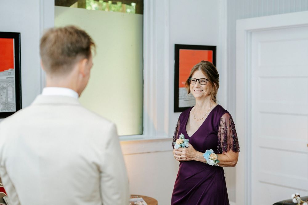 People gather in a bright hallway during wedding preparations with white doors in the background.