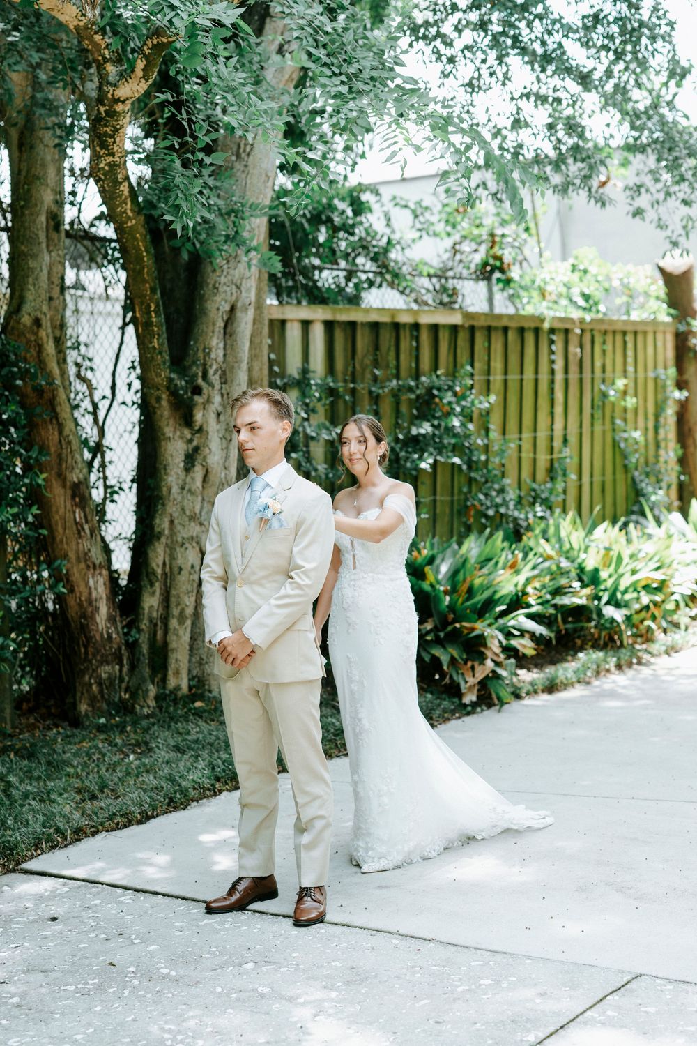 Wedding couple shares a moment on a garden pathway surrounded by lush greenery.