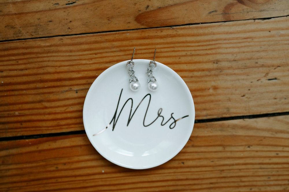 Row of decorative white ceramic plates displayed on rustic wooden planks with whimsical text designs.