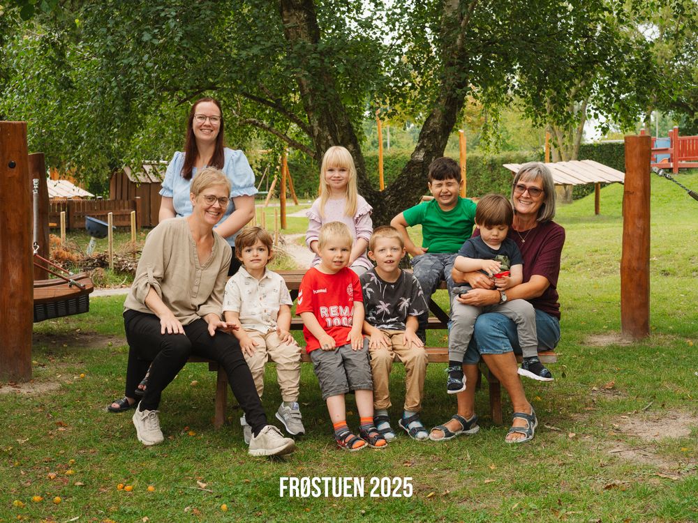 People sitting together outdoors on wooden benches at a summer gathering in a park setting.