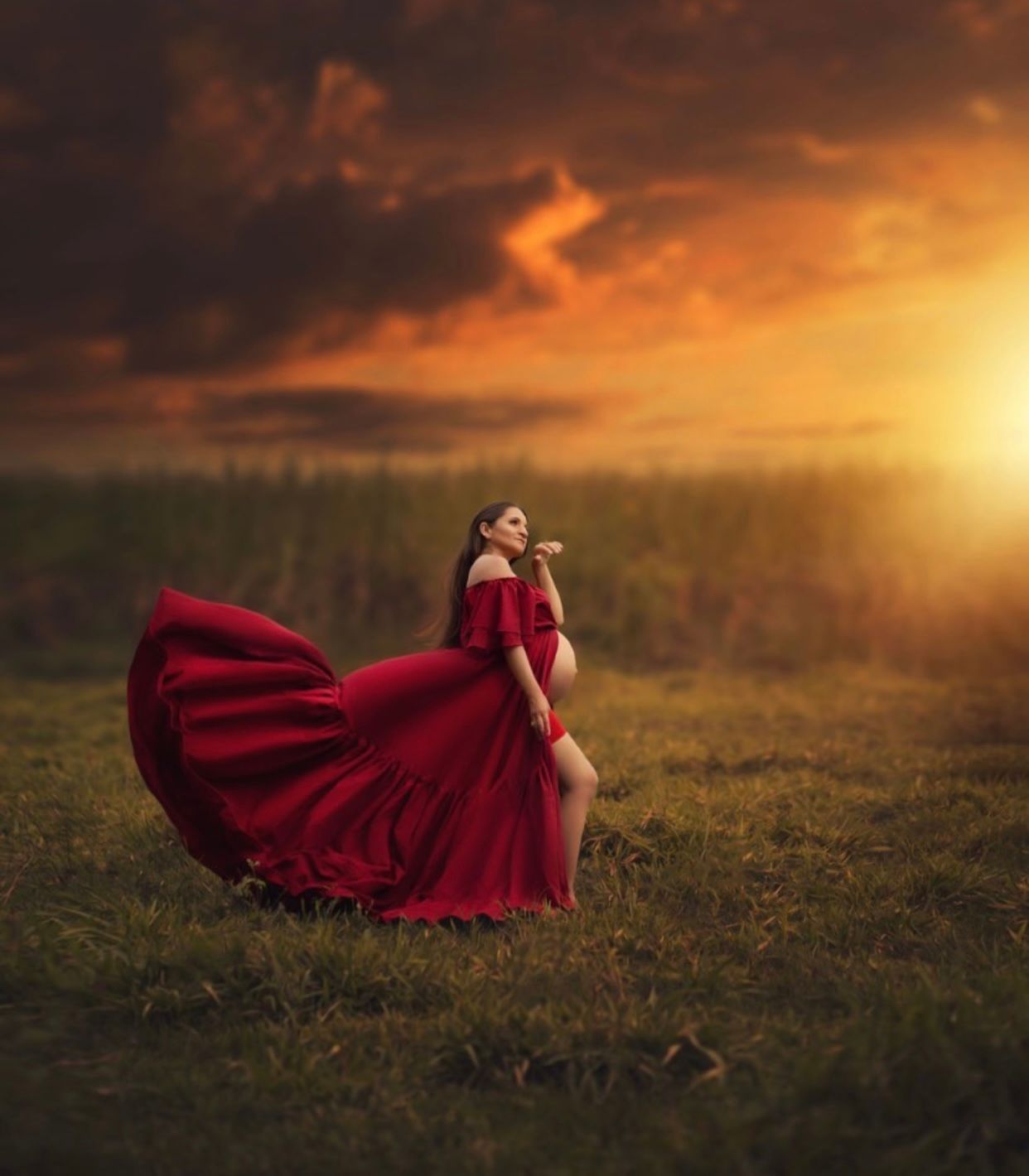 Dramatic sunset portraits of flowing red dress in golden field.