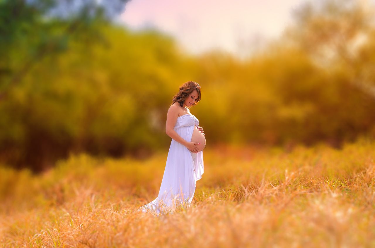 Client in white dress walking through golden field at sunset creating dreamy atmosphere.