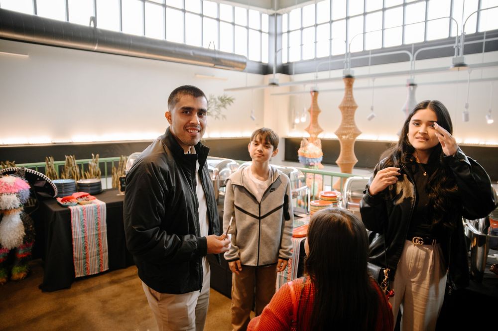 People gathered in a bright indoor space with tall windows and wooden decor.