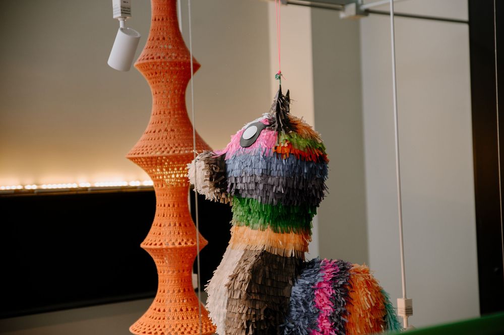 Decorative display featuring a tall orange sculptural tower and colorful textured art piece against white wall.